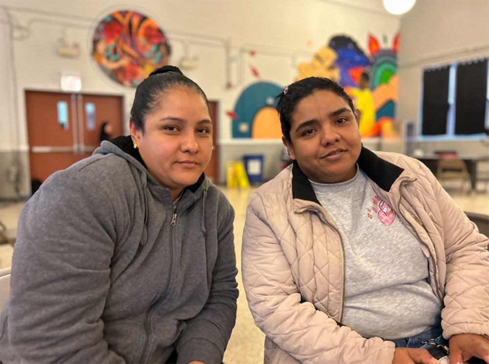 sisters Elizabeth Romero and Yusmery Marin sitting next to each other inside a Red Cross shelter.