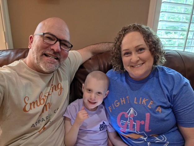 Emi and her parents post treatment smiling.