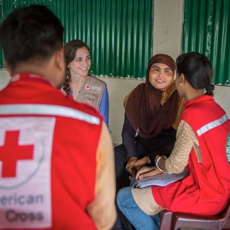 3 Red Cross volunteers speaking with lady