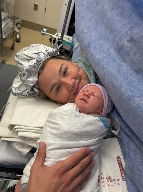 Tessa Troike-Barnett, lying in a hospital bed and holding her new born daughter, Dani.