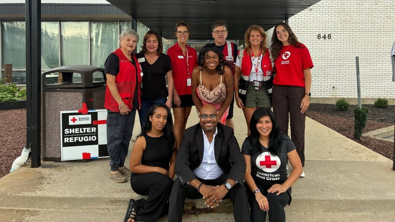 volunteers stand in front of red cross shelter