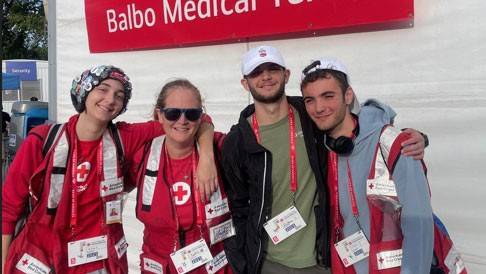 group picture of the Speciale Family wearing Red Cross vests and standing next to the Balbo Medical Tent.