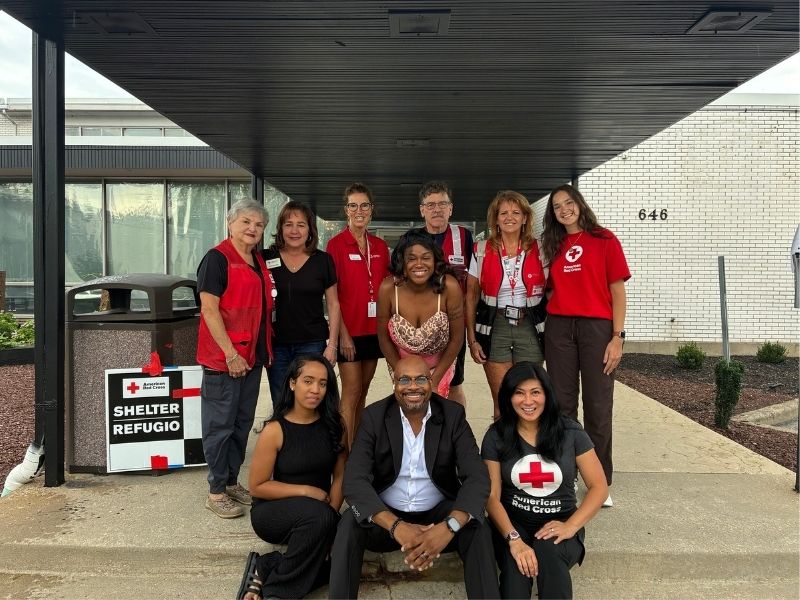 staff members and red cross volunteers stand in front of shelter