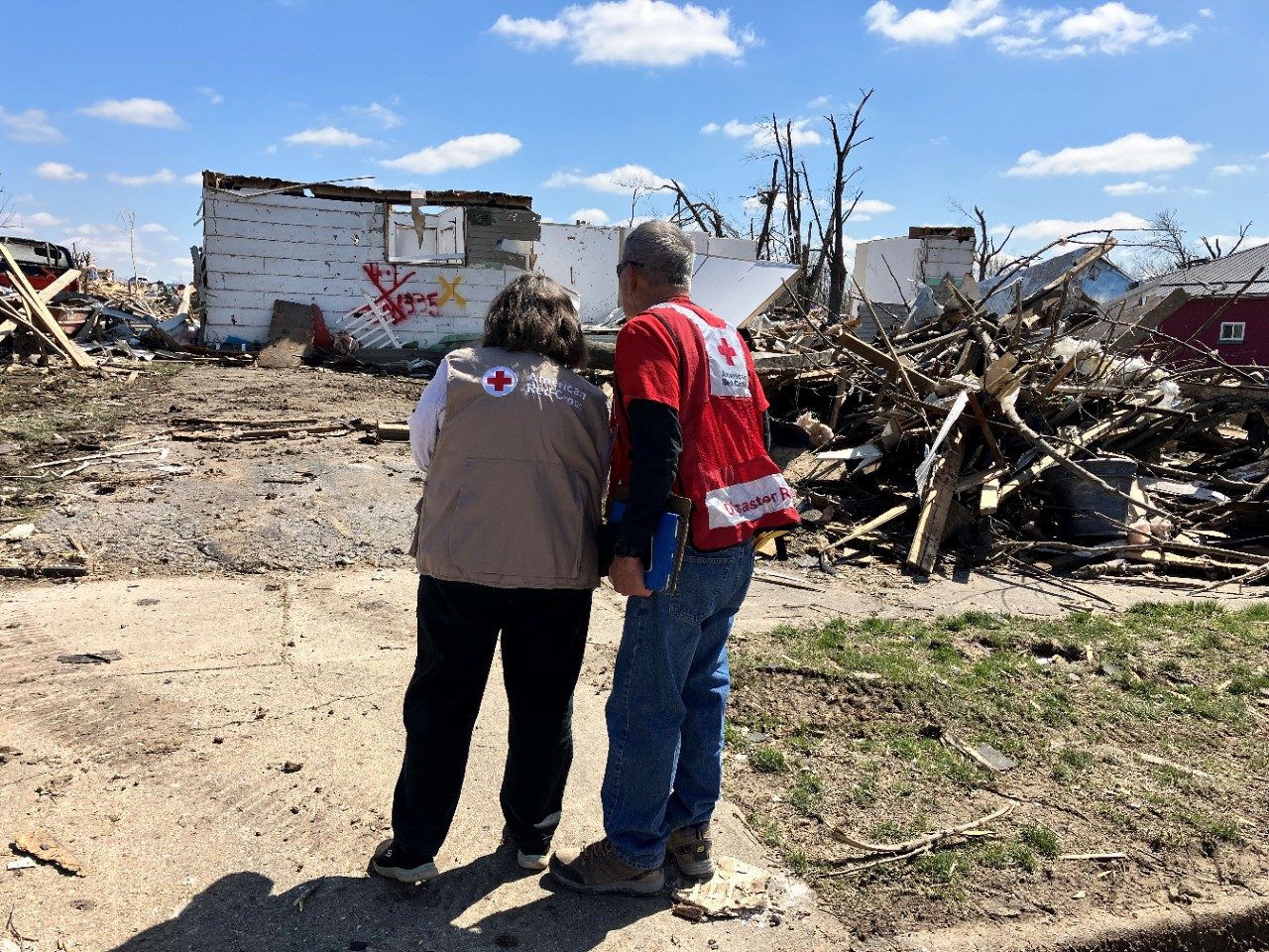 Two individuals standing, tornado damage 