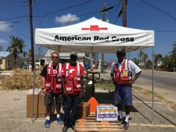 A group of men standing under a red cross tent
