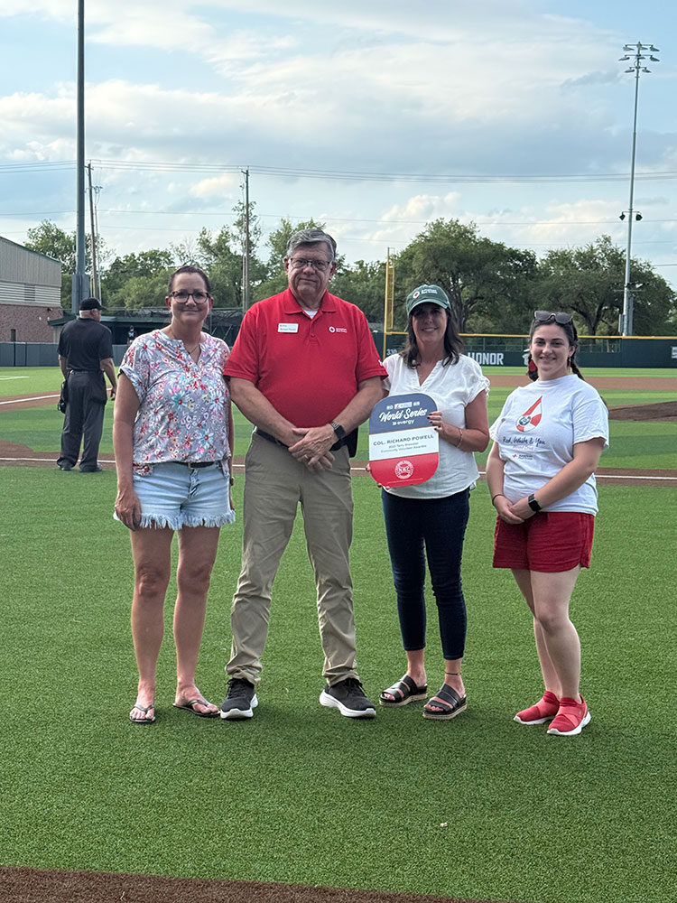Terry Brewster standing next to 3 other people with one holding the Terry Brewster award on a basball field.