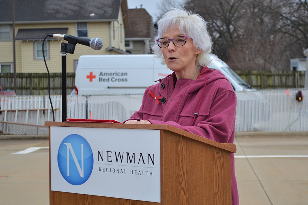 Susan Faler speaking at a podium outside.