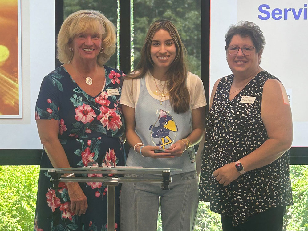 Daniella Beers being presented the 2025 volunteer award on stage at an event.
