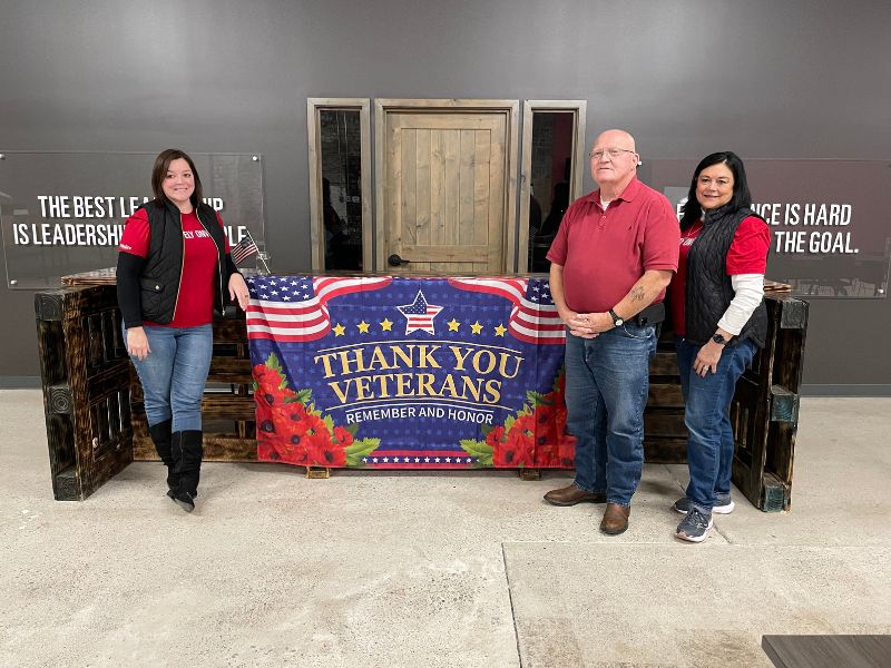 red crossers standing in front of a "thank you veterans" banner