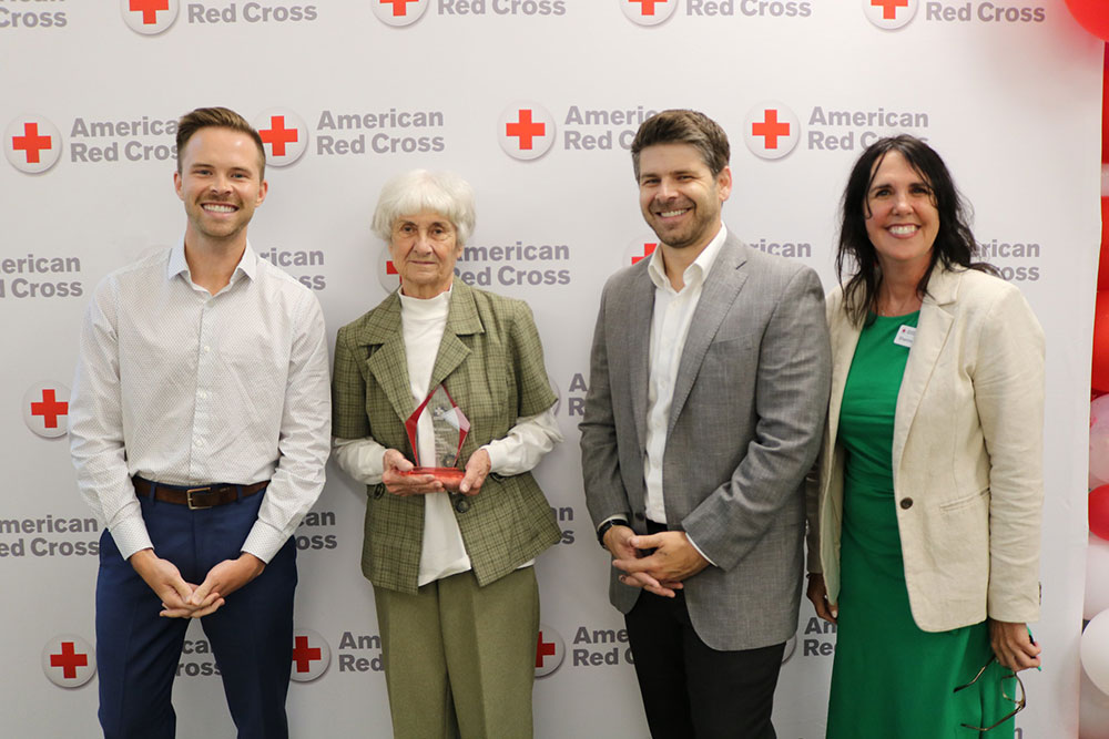 Roberta Johnson holding a Red Cross award and standing next to three Red Cross staff members.