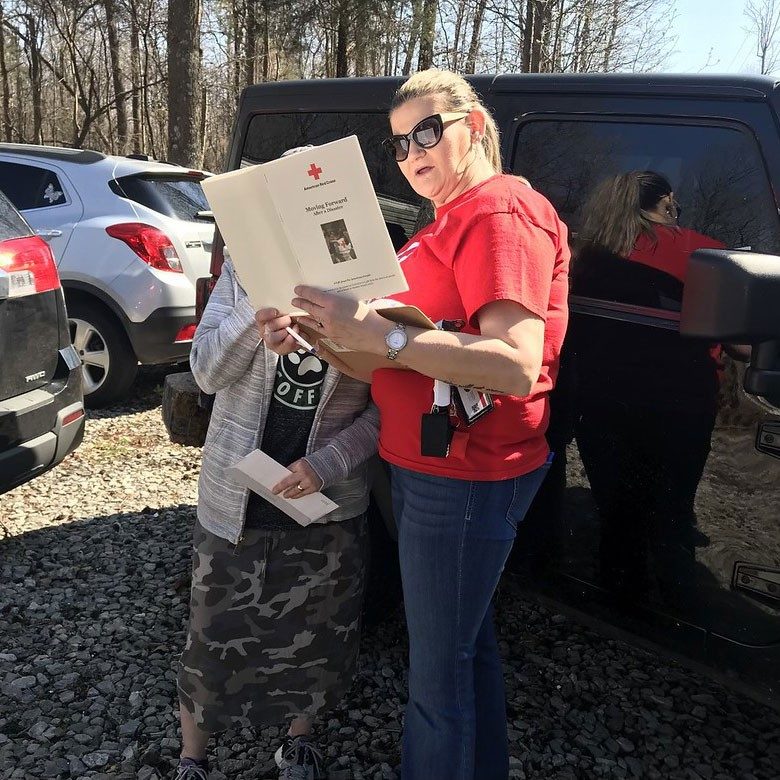 Red Cross volunteer looking at disaster guide with someone.