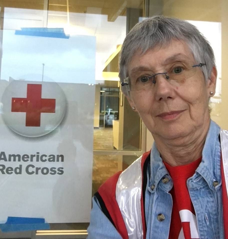A Red Cross volunteer with the American Red Cross logo in the background.