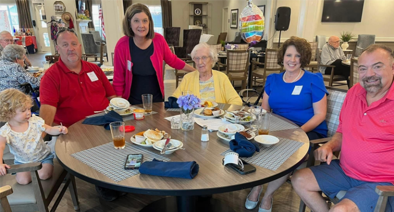 A family smiles at the camera from around a table.