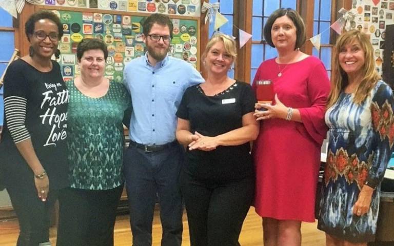Six Red Crossers in business casual dress smile at the camera at a volunteer recognition event.