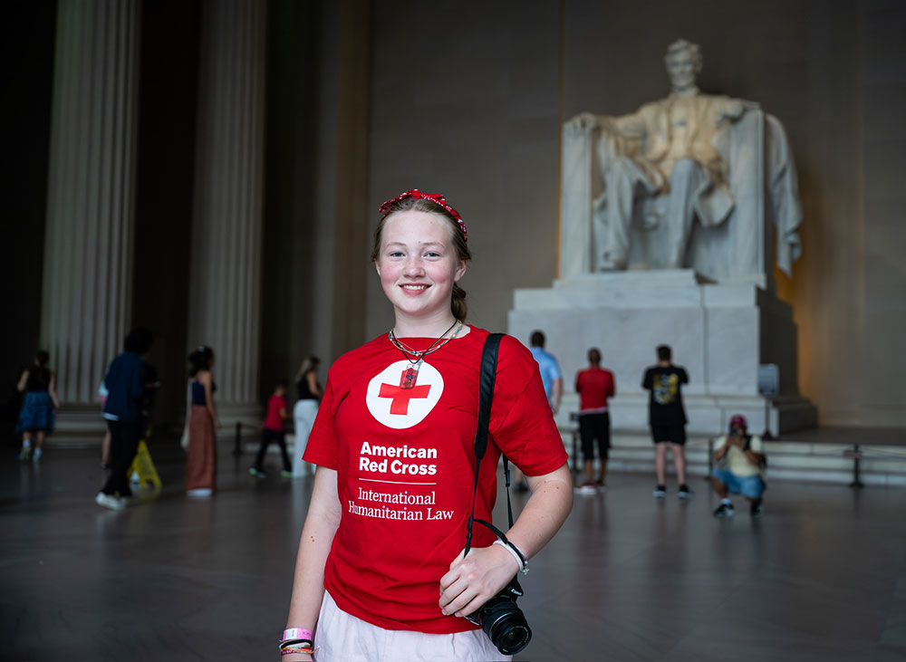 Raina Benz wearing a Red Cross shirt with the sculpture of Abraham Lincoln in the background at the Lincoln Memorial Chamber.