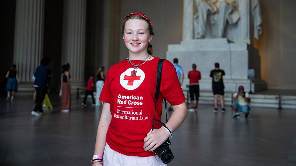 Raina Benz wearing a Red Cross shirt with the sculpture of Abraham Lincoln in the background at the Lincoln Memorial Chamber.