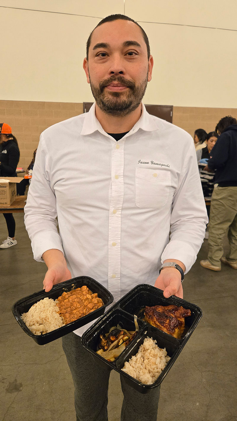 Chef Jason Yamaguchi holding prepared food for people at a shelter.