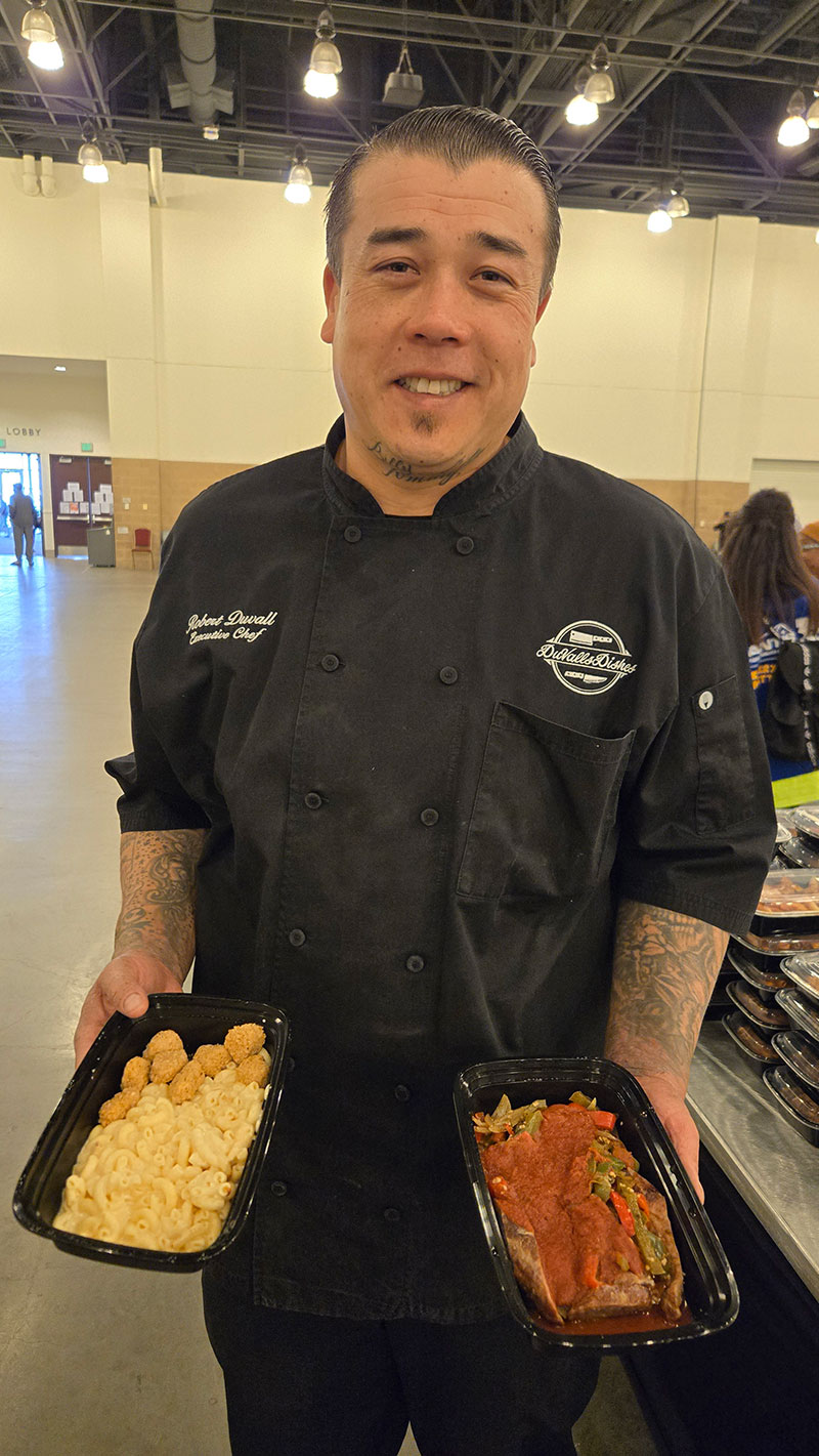 Chef Robert Duvall holding prepared food for people at a shelter.