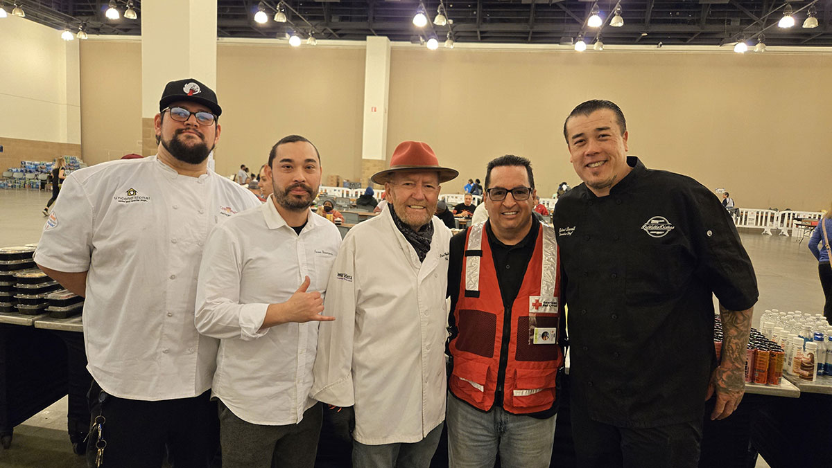 Group picture of chefs Pascal Olhats, Jason Yamaguchi, Robert Duvall and Anthony Mendez standing with a Red Cross volunteer in a shelter.