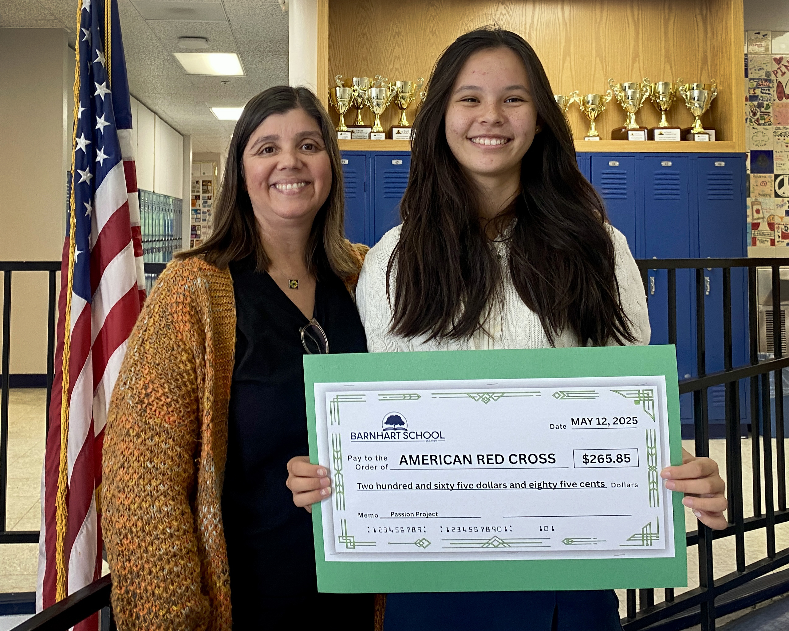 Teacher and student standing next to each other.  Student is holding a check made out to American Red Cross.