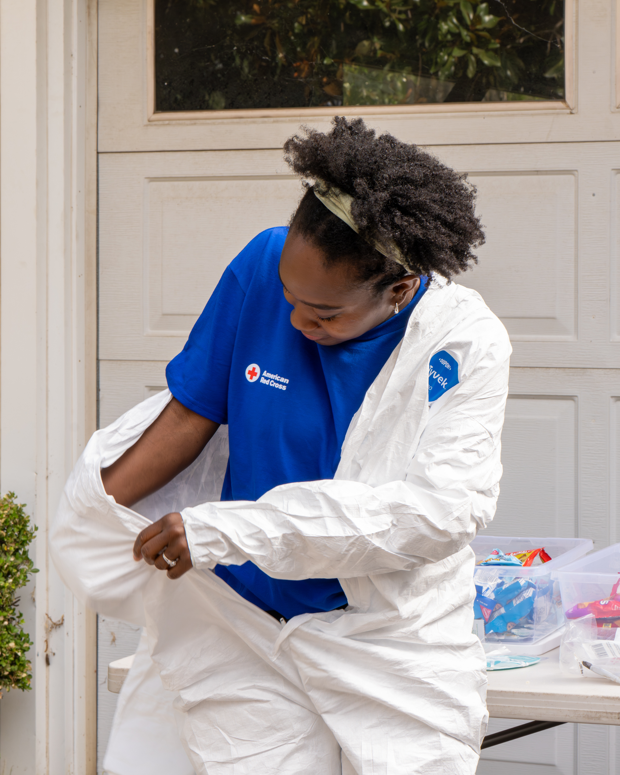 Lady in blue tee shirt puting on a white protective jumpsuit