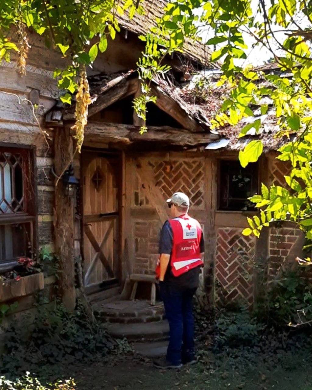 Red Cross volunteer wearing sun glasses at front door of home.
