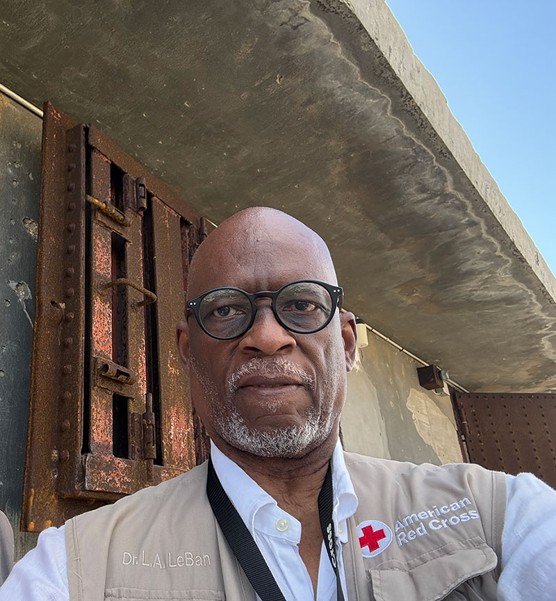 Dr. Levon Aldon LeBan takes a selfie while wearing a Red Cross vest and glasses.