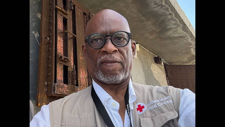 Dr. Levon Aldon LeBan takes a selfie while wearing a Red Cross vest and glasses.