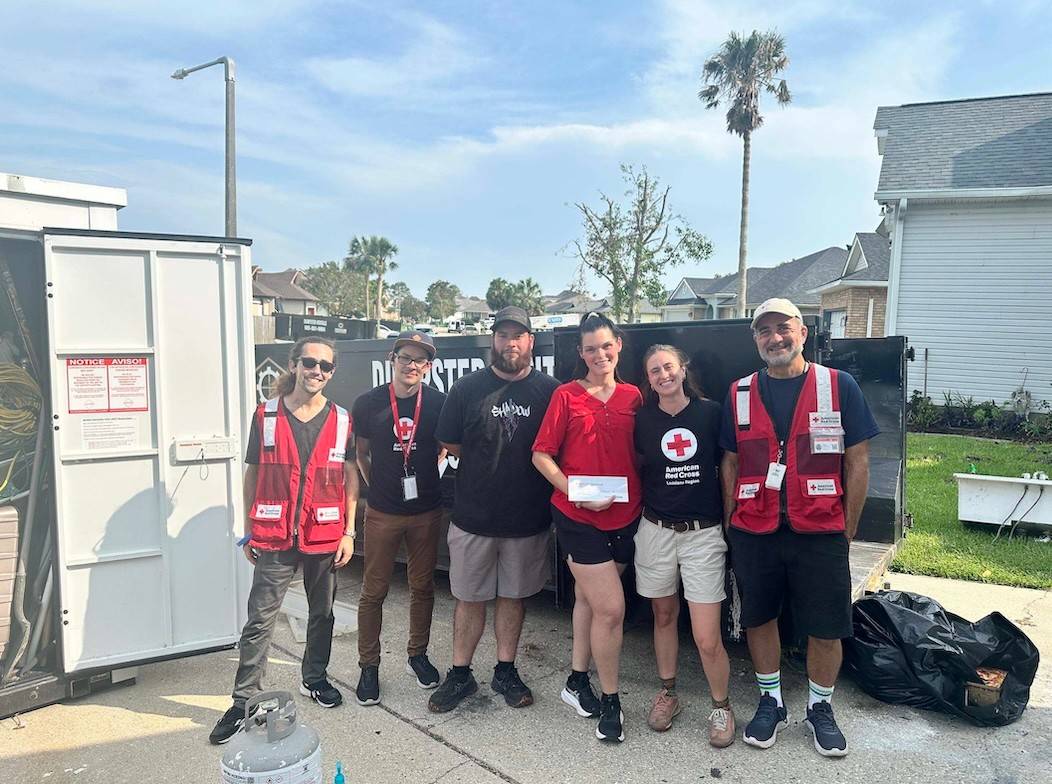 Red Cross volunteers stand with family