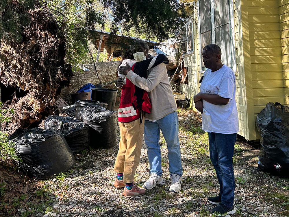Ellis Neal hugging a Red Cross volunteer while standing next to his house.