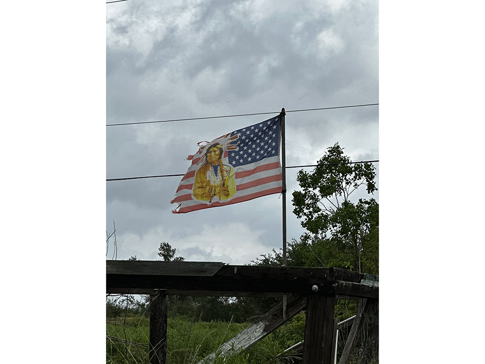 An American flag with a native American on it billows in the wind..