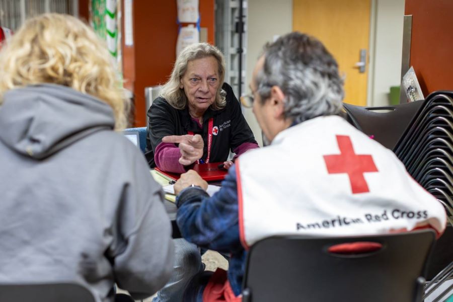 Red Cross volunteer talking to two clients.