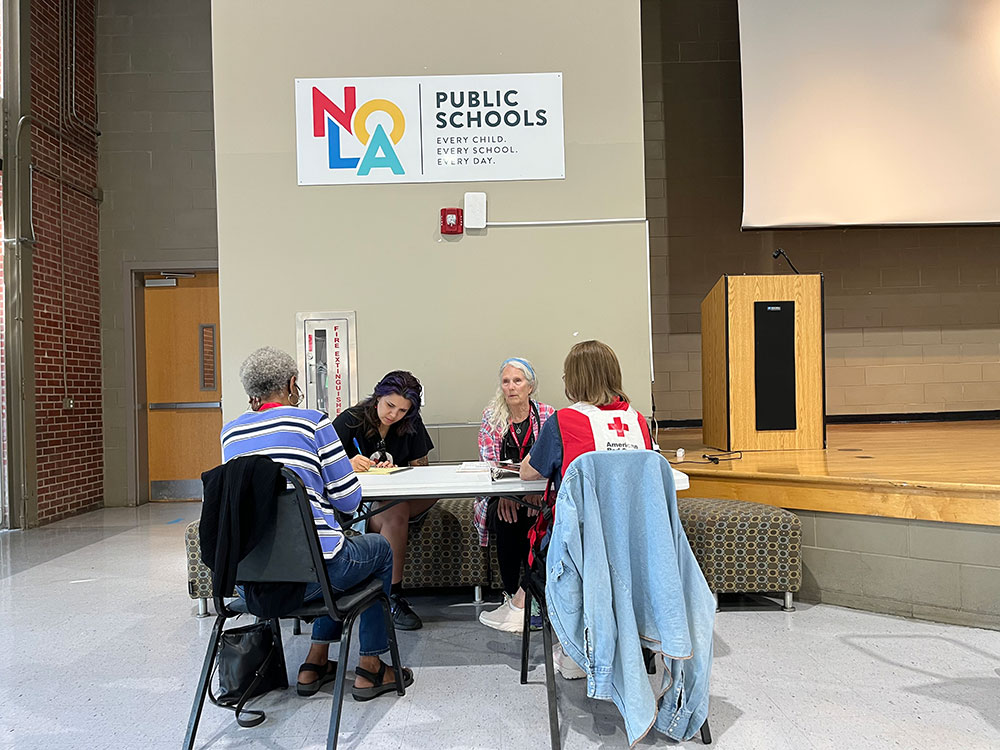 Red Cross volunteers sitting at a table working on paperwork in a room.