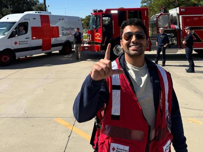 mihir in red cross volunteer uniform holding peace sign