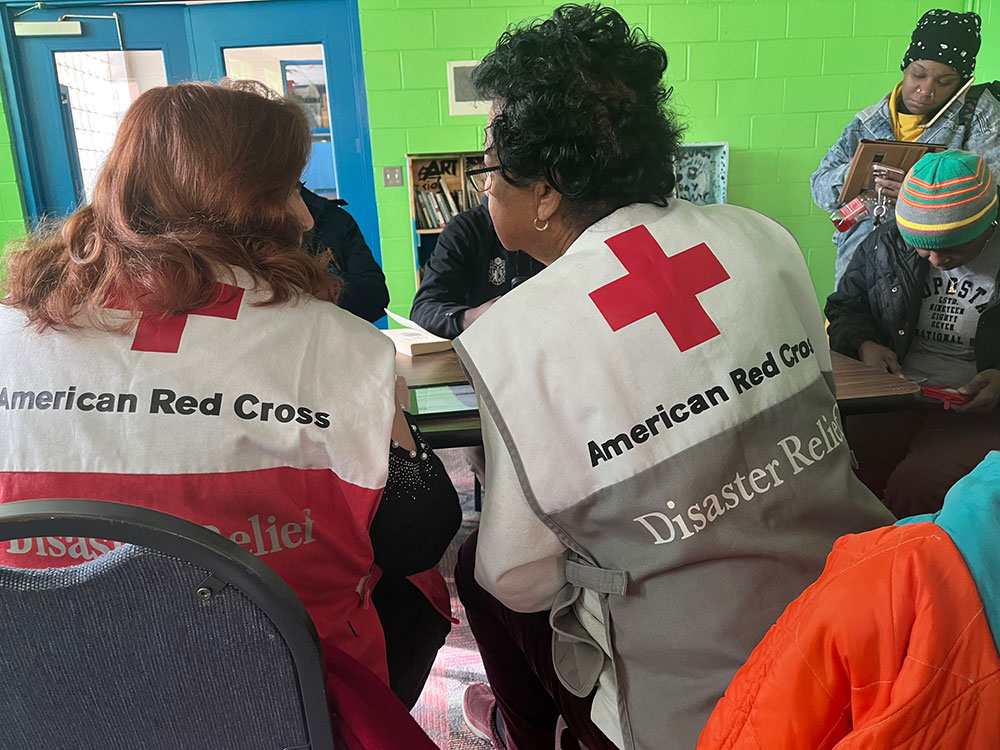 Red Cross volunteers sitting at a table in a shelter.