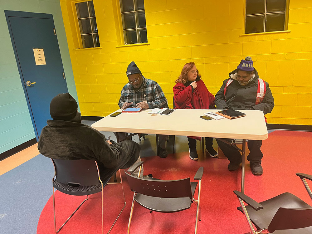 residents sitting at a table in a shelter.