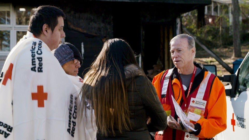 red cross volunteer talking to two people