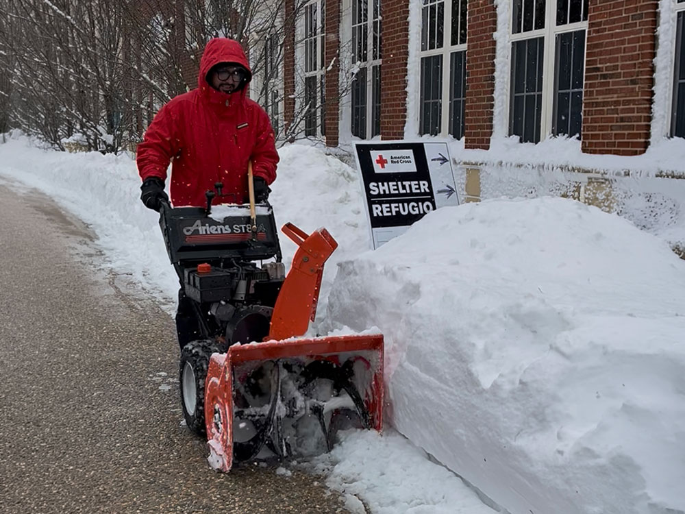 Man operates snow blower at emergency shelter.