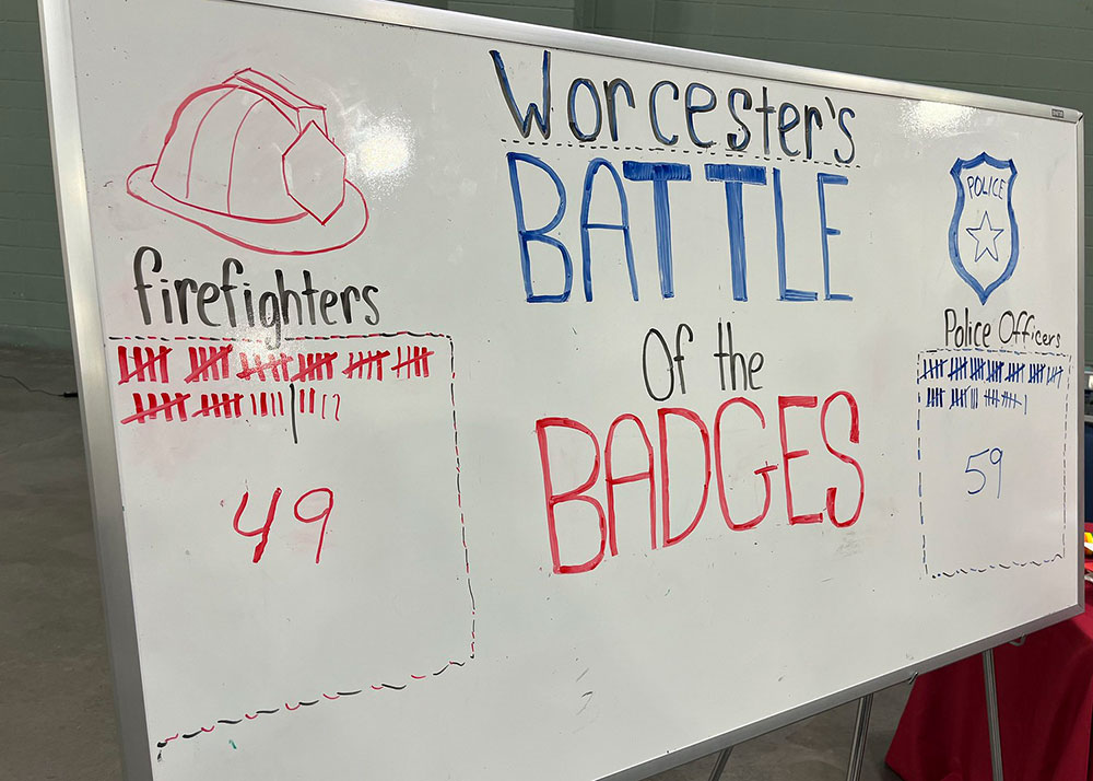 a white board with the battle of the badges score between the firefighters and police officers.