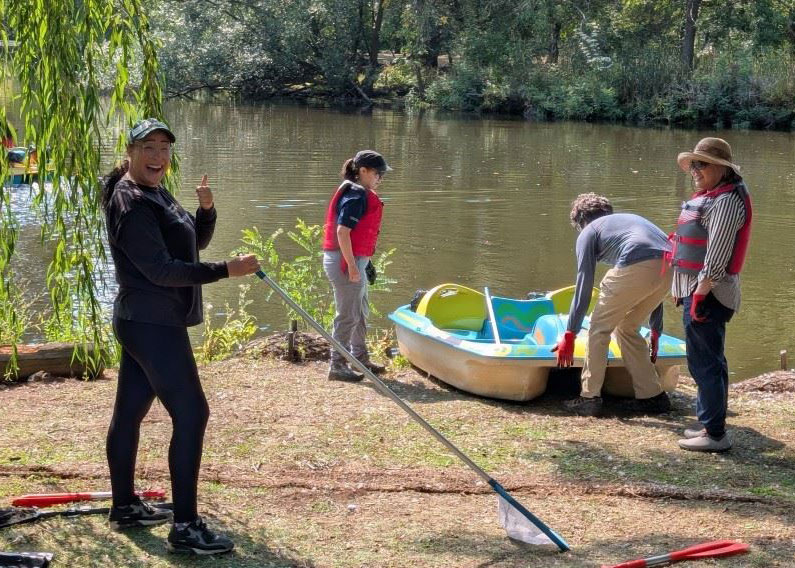 Volunteers next to a pedal boat about to be pushed onto a lake.