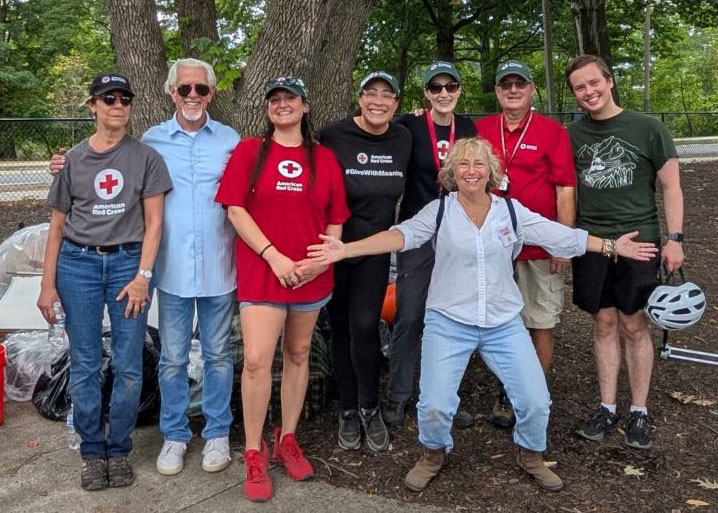 Eight volunteers take a group pic next to a tree.