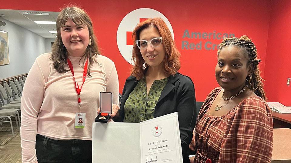 Yvonne Armando, holding her Certificate of Merit, standing next to Nia Rennix, Executive Director of the Red Cross Central-Western MA Chapter; and Nicole Barbosa, Community Disaster Program Manager for Western MA.