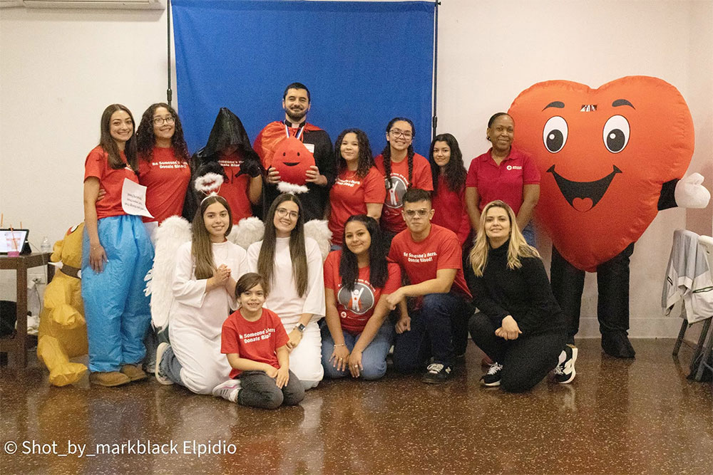 a group picture of blood donors and a heart shaped mascot.