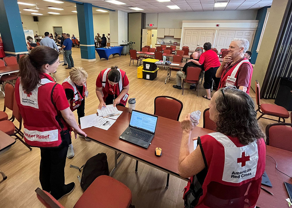 Room full of Red Cross volunteers with tables and chairs.