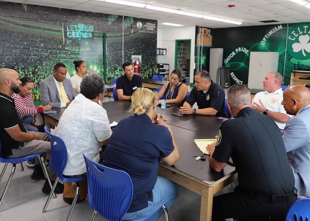 firefighters and other people sitting at a table talking to each other.