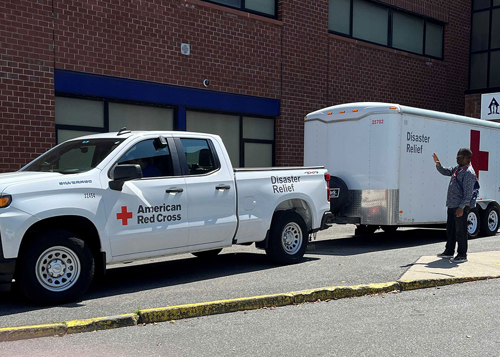 Red Cross Disaster Relif truck and trailer next to a brick building.