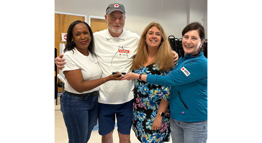Red Cross staff members and volunteers holding a Red Cross award.