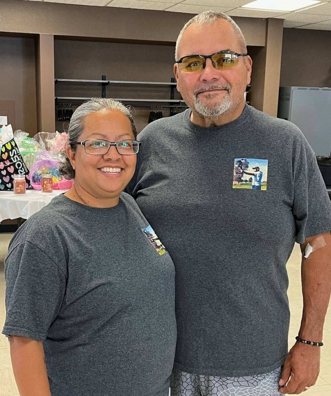 Raquel and Blass Ybarra both wearing glasses with a table of presents behind them.