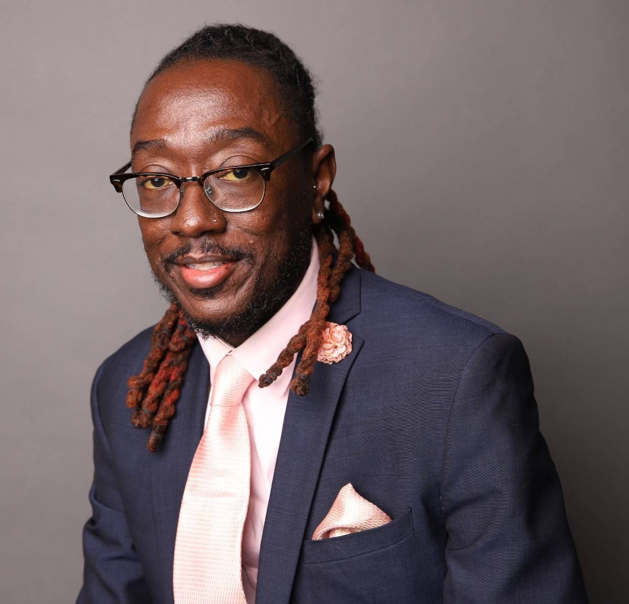 Clinton Kirkman, sickle cell patient and advocate, wearing glasses and a suit