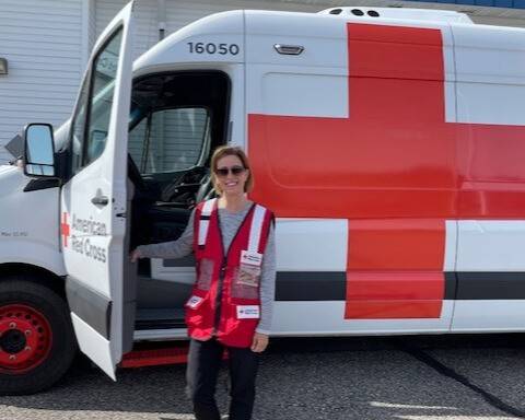 Photo of Mickie Mohs in front of a Red Cross disaster relief truck.